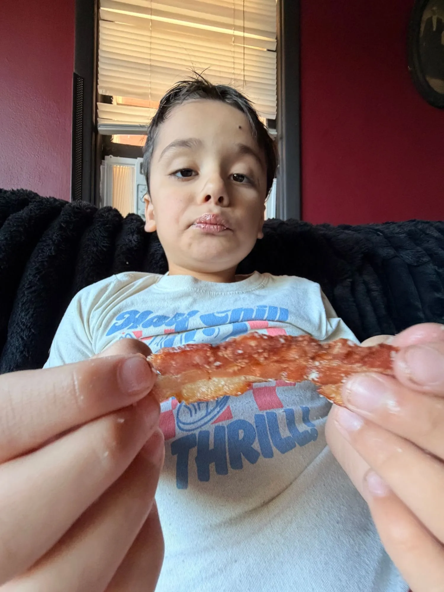 Remy holding up a crispy strip of bacon sprinkled with parmesan cheese